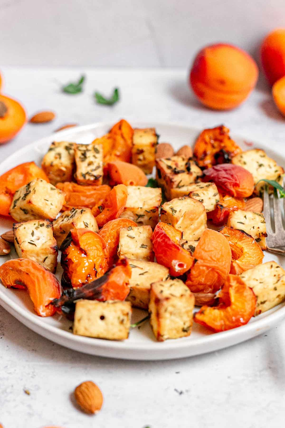 Grilled tofu and apricots removed from the skewers, on a plate.