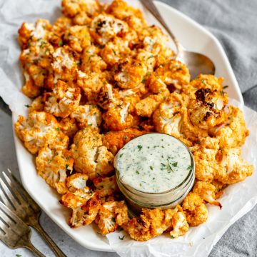 A platter of vegan air fryer buffalo cauliflower served with vegan ranch.