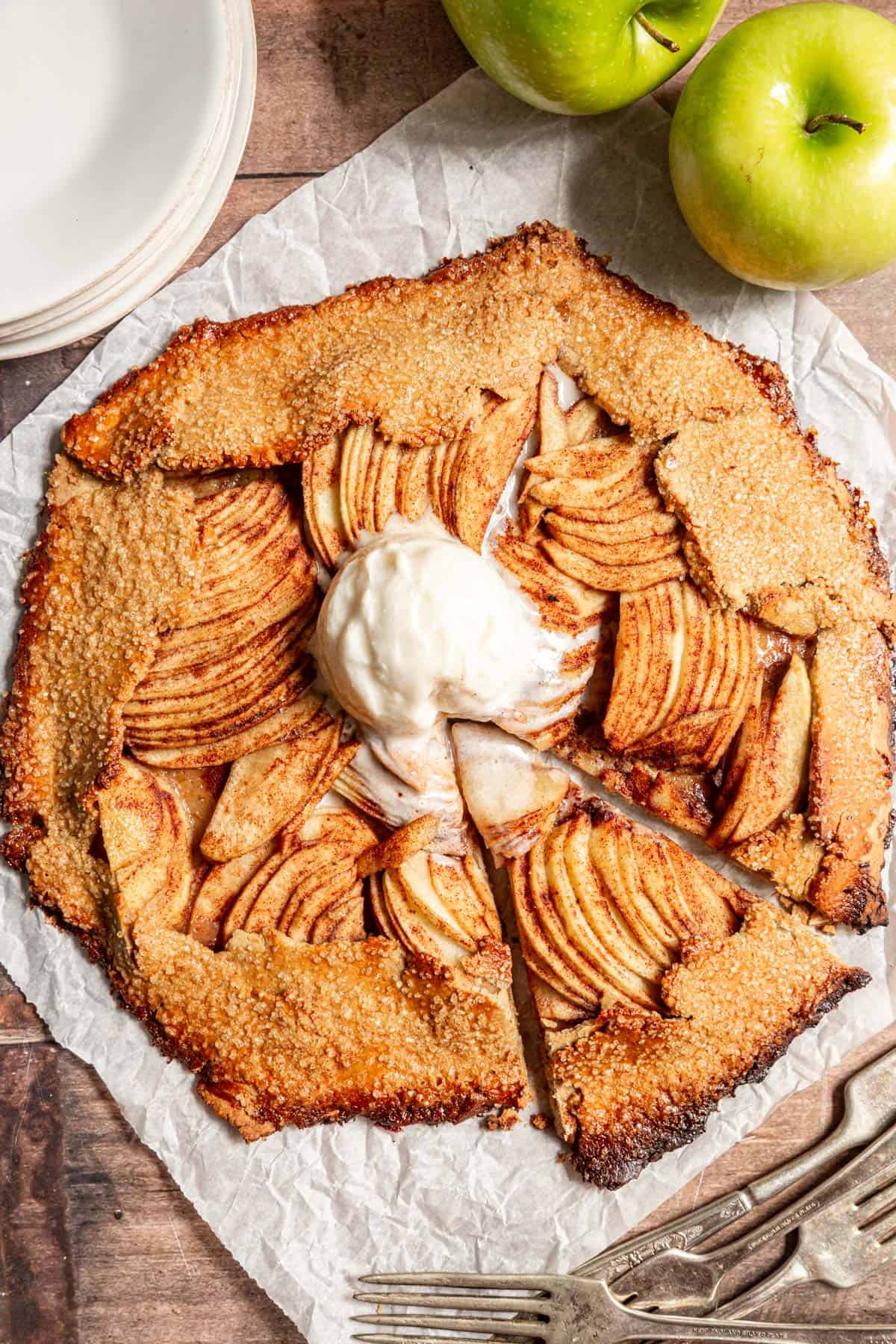 A Vegan Apple Galette with a scoop of ice cream, sliced, about to serve.