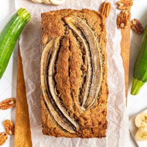 A loaf of vegan banana zucchini bread on a cutting board.