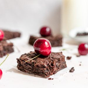 A vegan black forest brownie topped with a cherry.