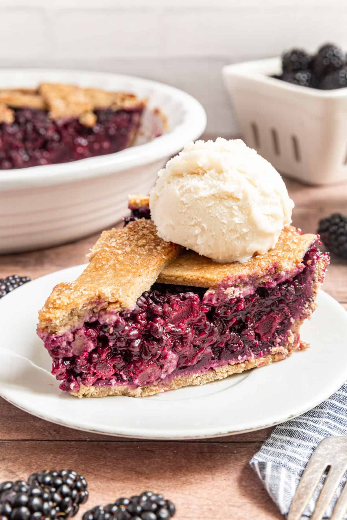A slice of Vegan Blackberry Pie topped with a scoop of ice cream.