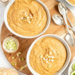 Two bowls of vegan cauliflower leek soup, with scallions, ready to serve.