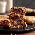 A stack of vegan chocolate filled cookies, broken in half to reveal the chocolate center.