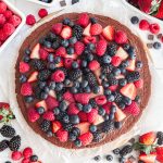 A vegan chocolate fruit pizza, ready to slice and serve.