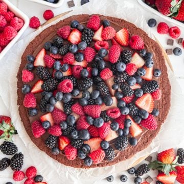 A vegan chocolate fruit pizza, ready to slice and serve.