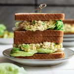 Two vegan egg salad sandwiches stacked on top of each other.