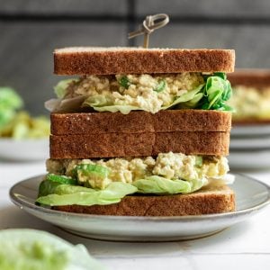 Two vegan egg salad sandwiches stacked on top of each other.