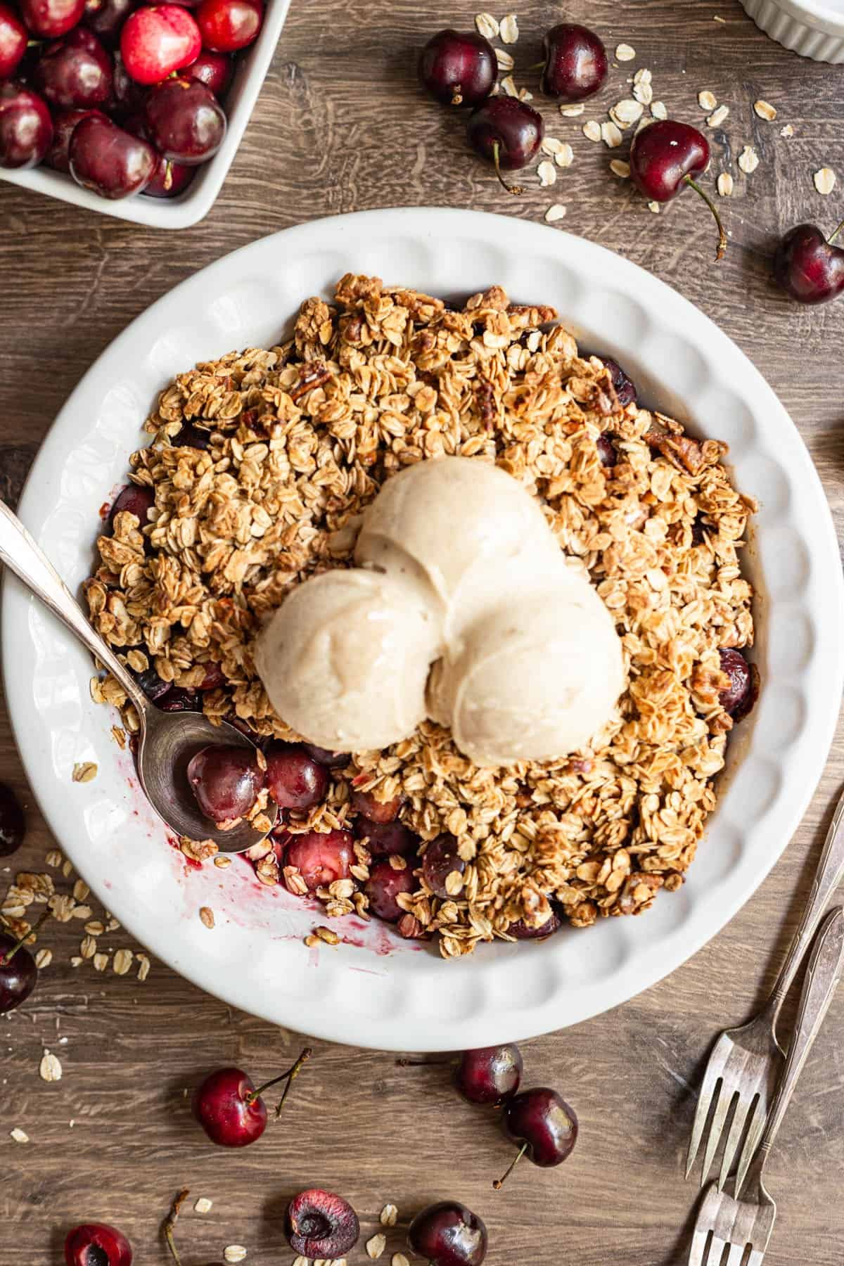 Vegan gluten free cherry crisp with a serving removed, highlighting bright red cherries.
