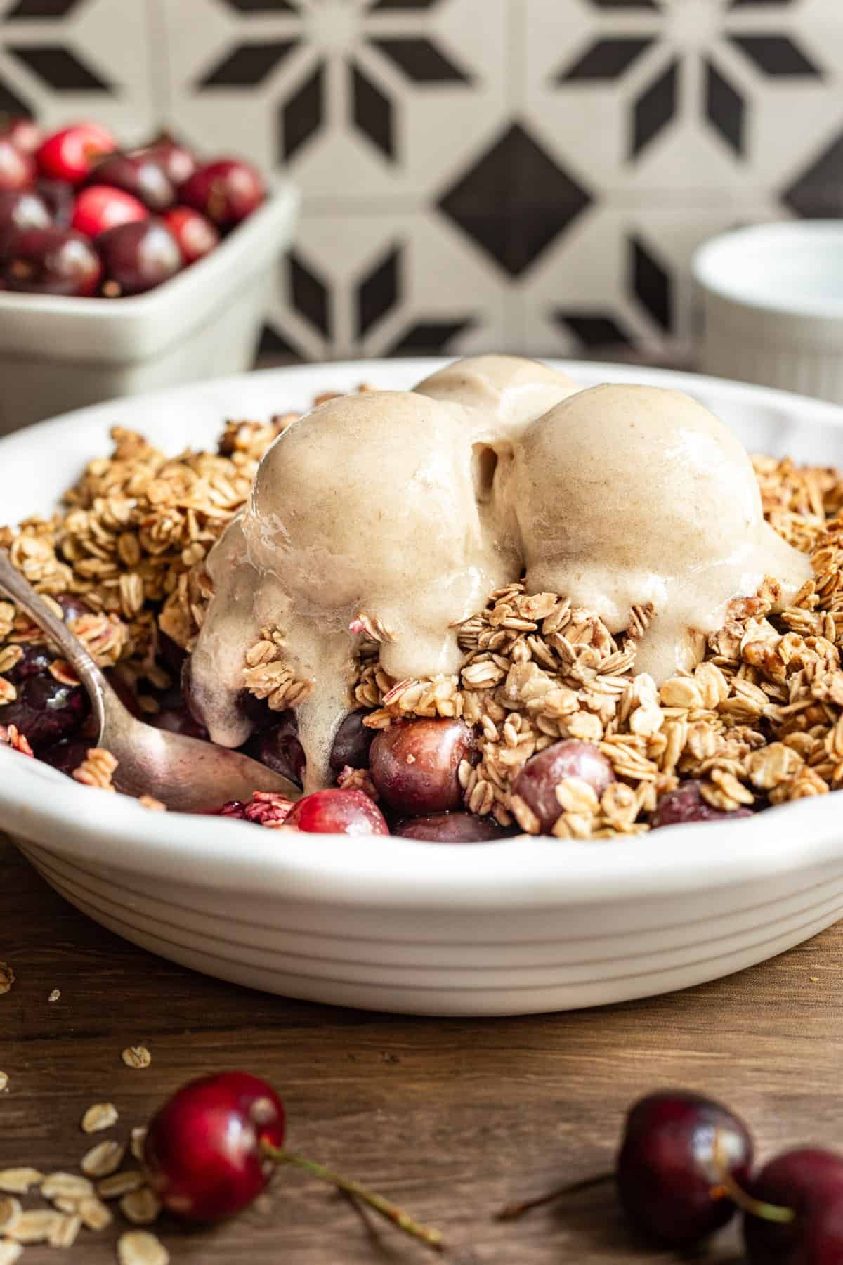 Vegan gluten free cherry crisp with a serving removed, highlighting bright red cherries.