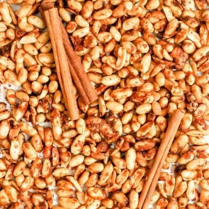 A tray of vegan honey roasted peanuts, with cinnamon sticks.