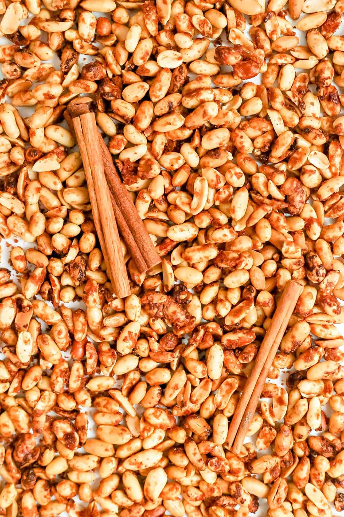 A tray of vegan honey roasted peanuts, with cinnamon sticks.