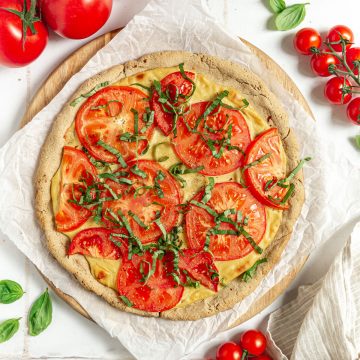 Vegan margherita pizza freshly baked and ready to slice.