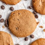A vegan chocolate chip cookie on a sheet of parchment paper.