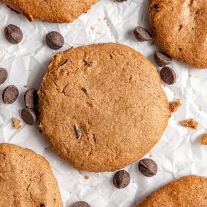 A vegan chocolate chip cookie on a sheet of parchment paper.