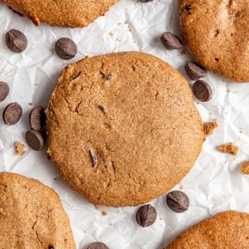 A vegan chocolate chip cookie on a sheet of parchment paper.