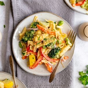 A plate of vegan pasta primavera, with a fork, ready to serve.