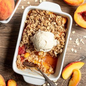 Peach crisp with a serving removed and a scoop of ice cream on top