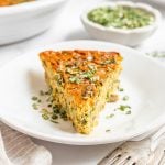 A slice of vegan crustless quiche topped with fresh chives.