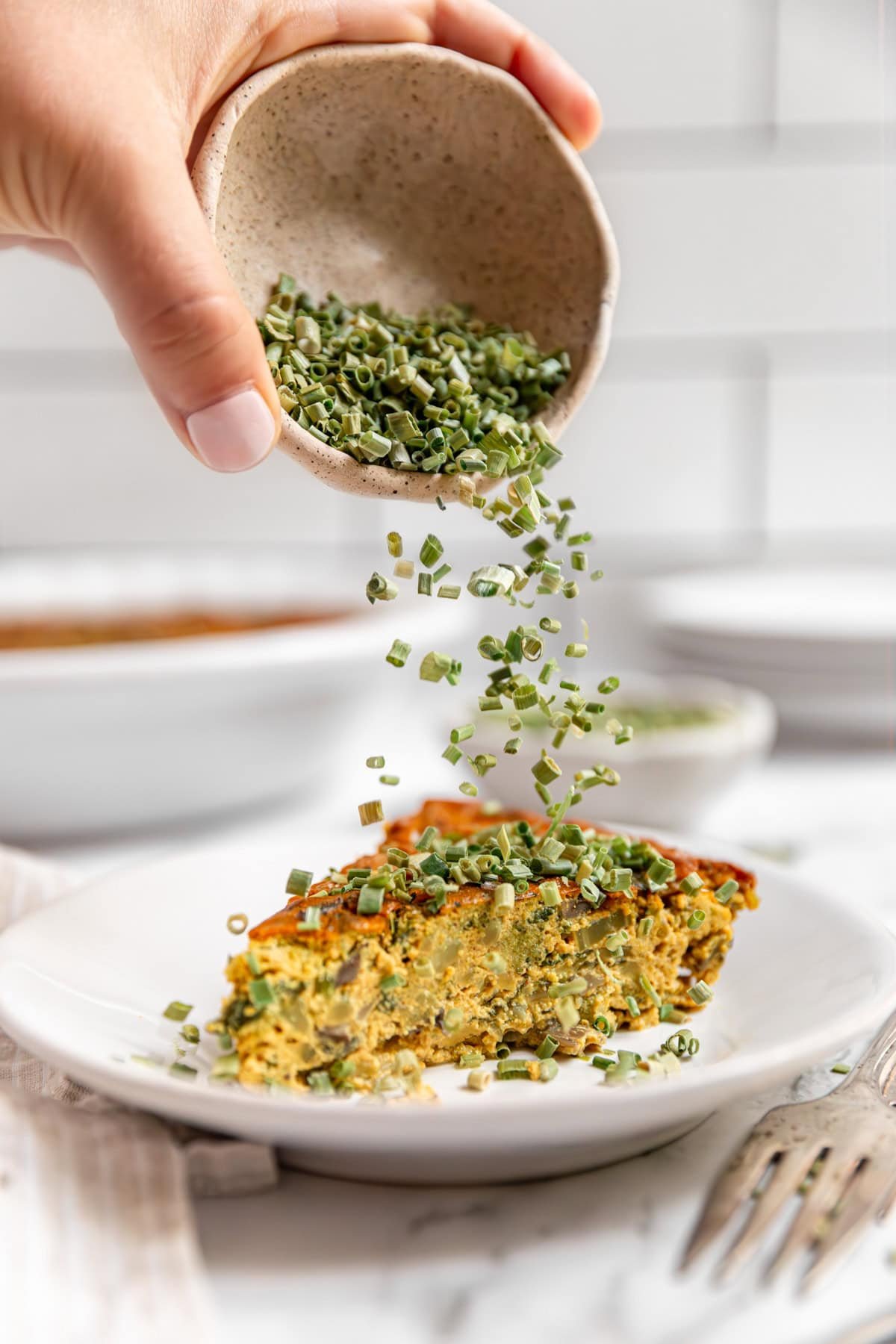 Chives sprinkled onto a slice of Vegan Crustless Quiche.