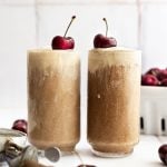 Two vegan root beer floats, topped with fresh cherries.