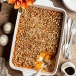 A dish of sweet potato casserole with a serving scooped out.