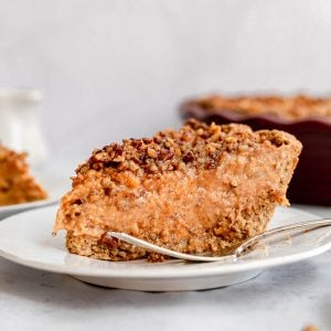 A slice of sweet potato pie on a plate with a fork,