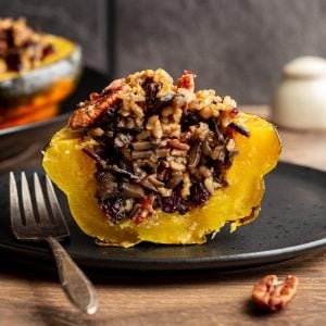A wild rice stuffed acorn squash sliced in half to reveal the rice inside.