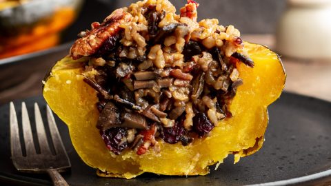 A wild rice stuffed acorn squash sliced in half to reveal the rice inside.