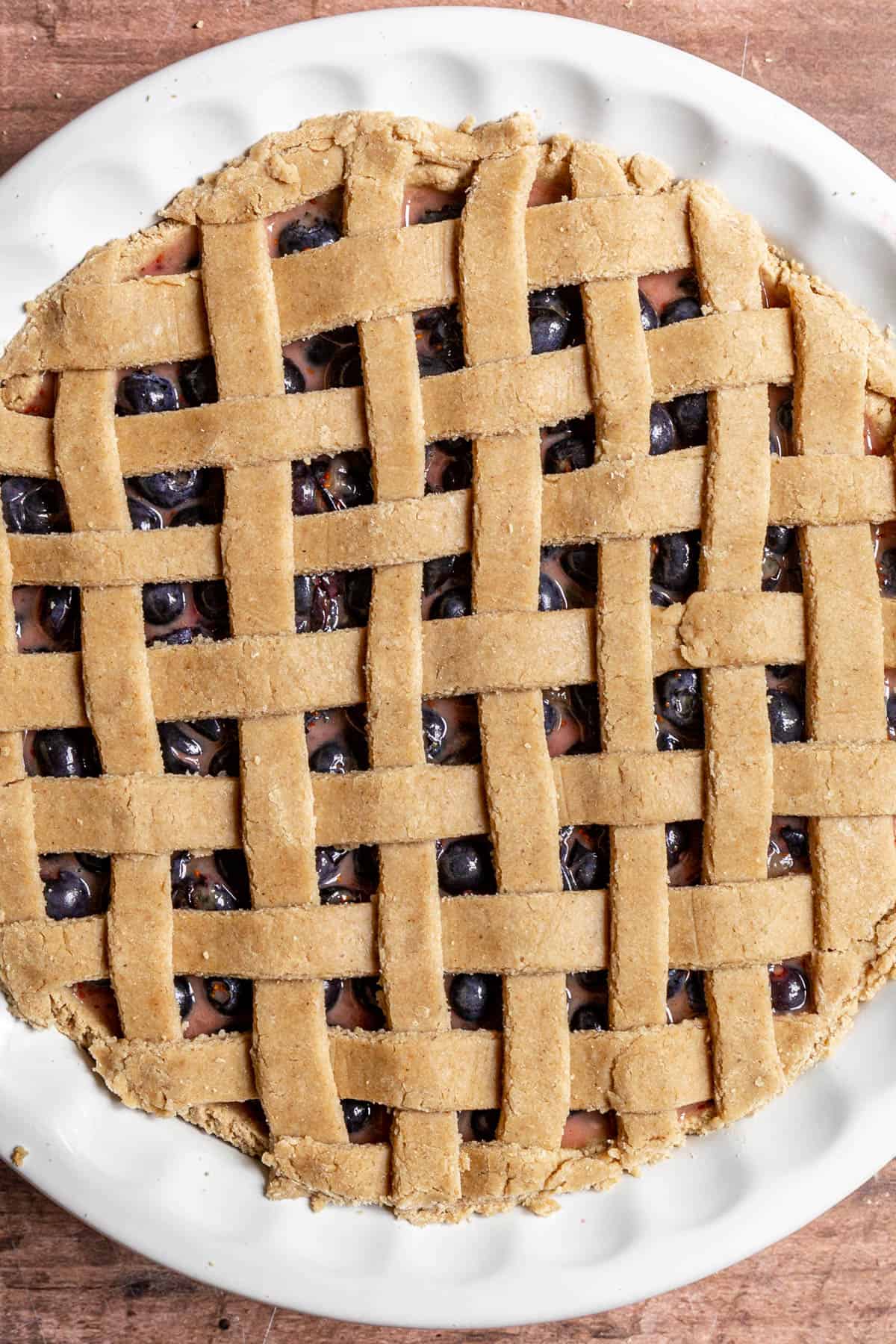 An unbaked blueberry pie with an intricate lattice made from WFPB pie crust.