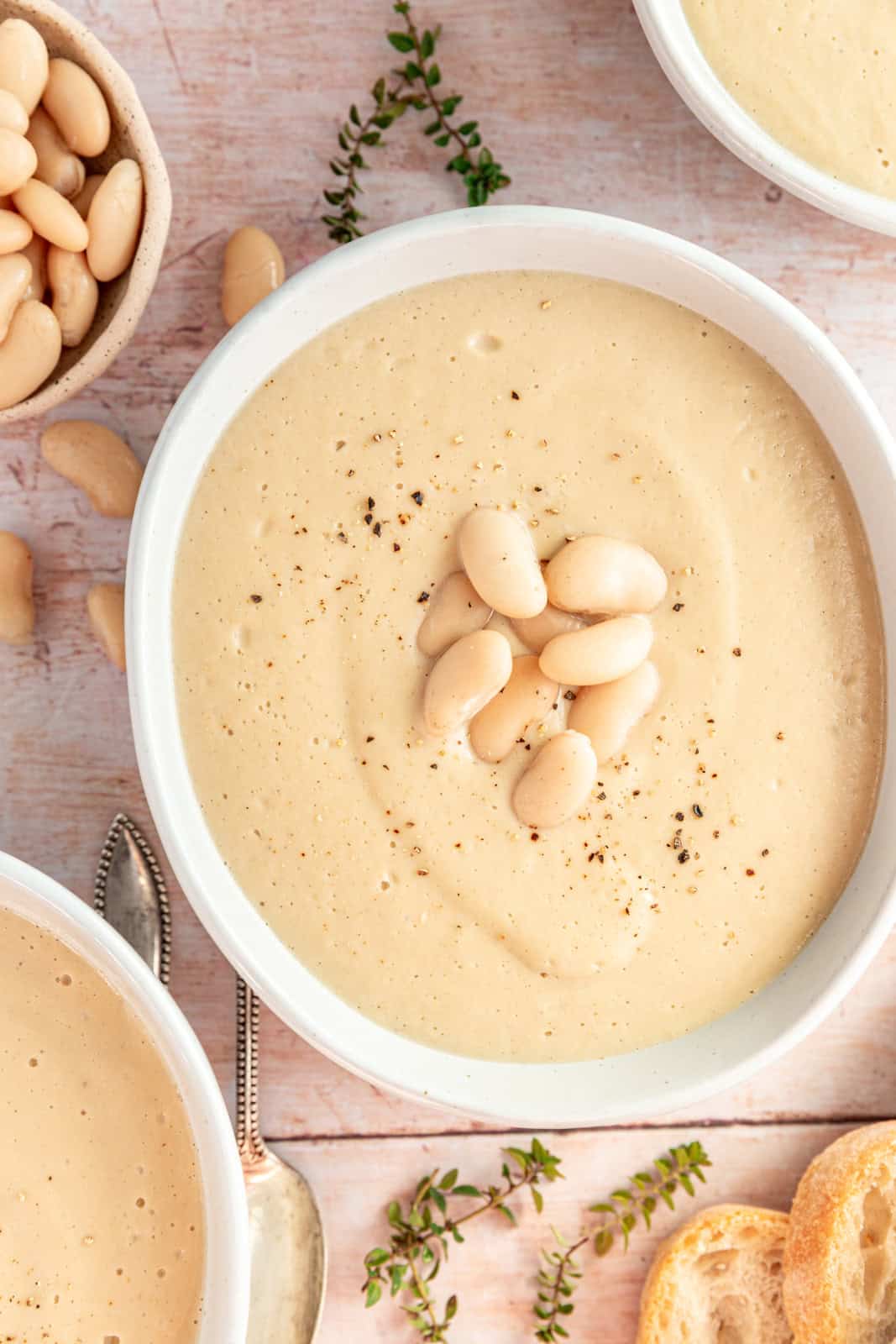 Bowls of Creamy Cauliflower White Bean Soup with white beans and thyme.