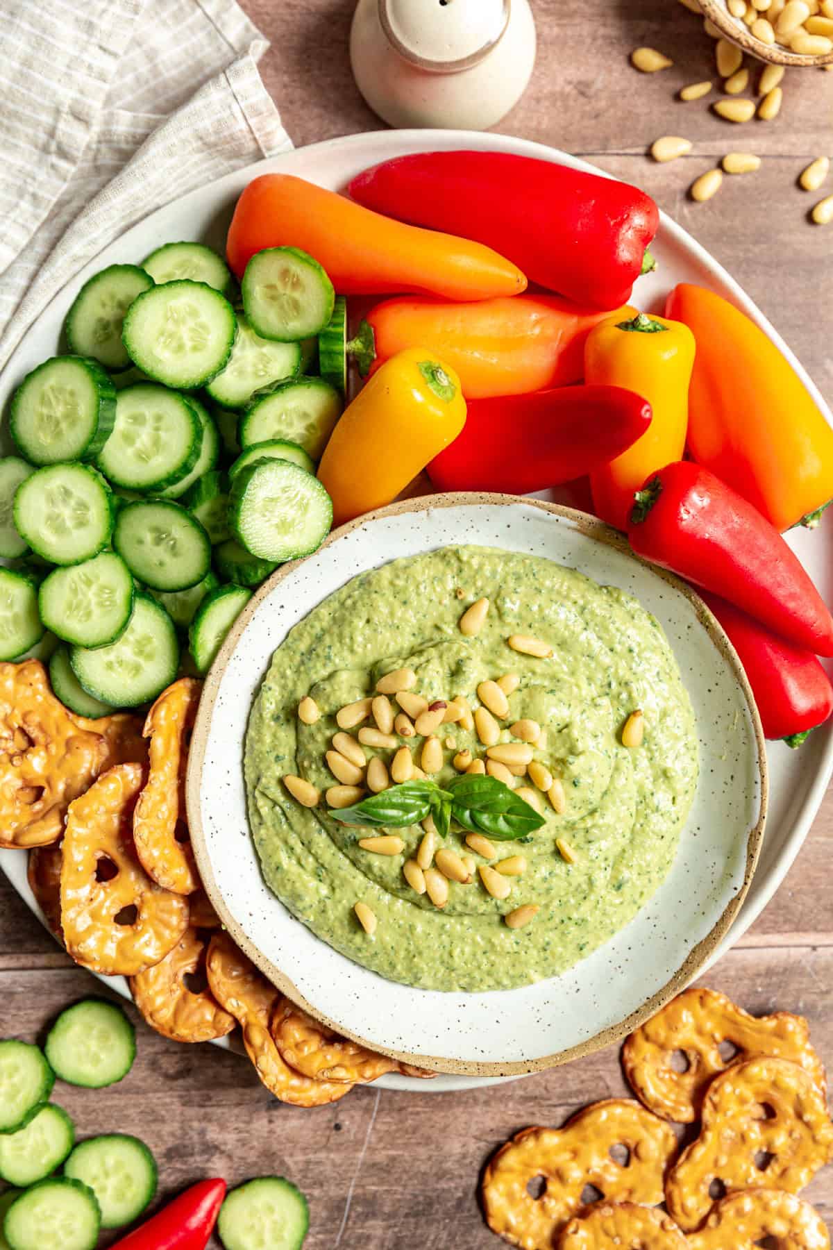 Vegan White Bean Pesto Dip in a bowl served with fresh vegetables.