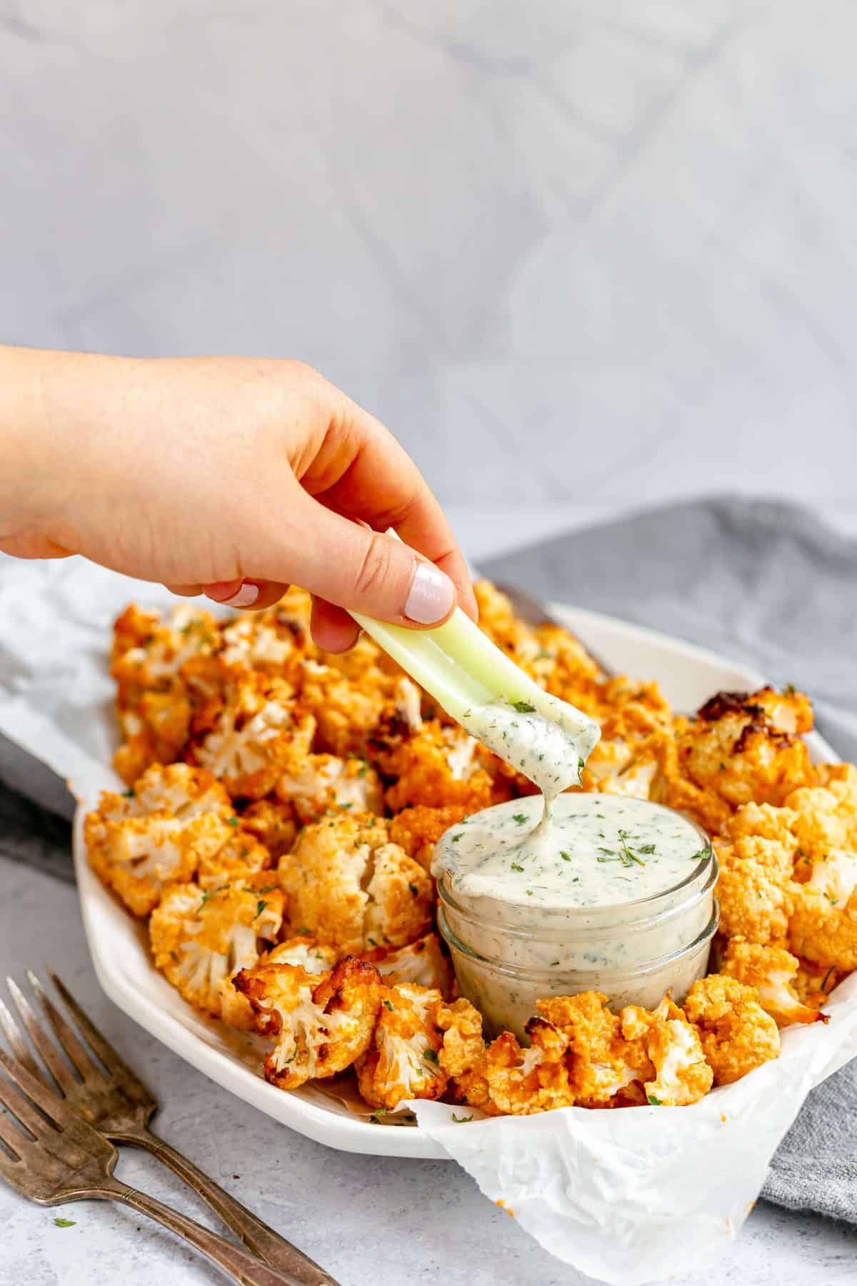 Celery being dipped in Easy Plant-Based Ranch Dip