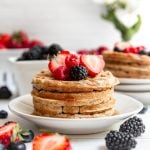 A stack of oat flour waffles topped with fresh berries.