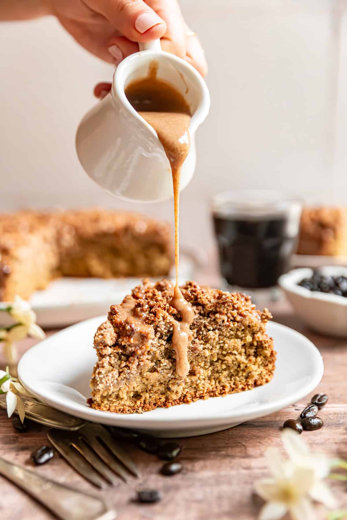 A piece of vegan coffee cake being drizzled with glaze.