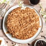 Vegan coffee cake on a large plate, drizzled with glaze, ready to slice.