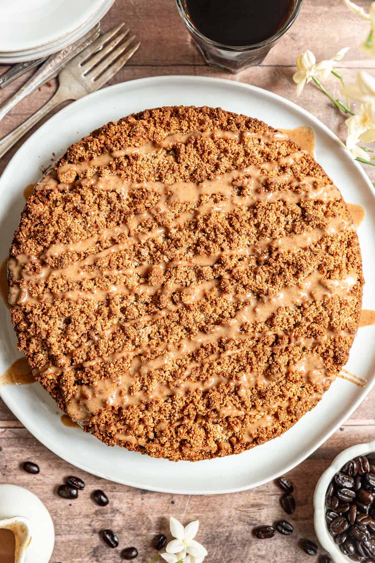Vegan coffee cake on a large plate, drizzled with glaze, ready to slice.