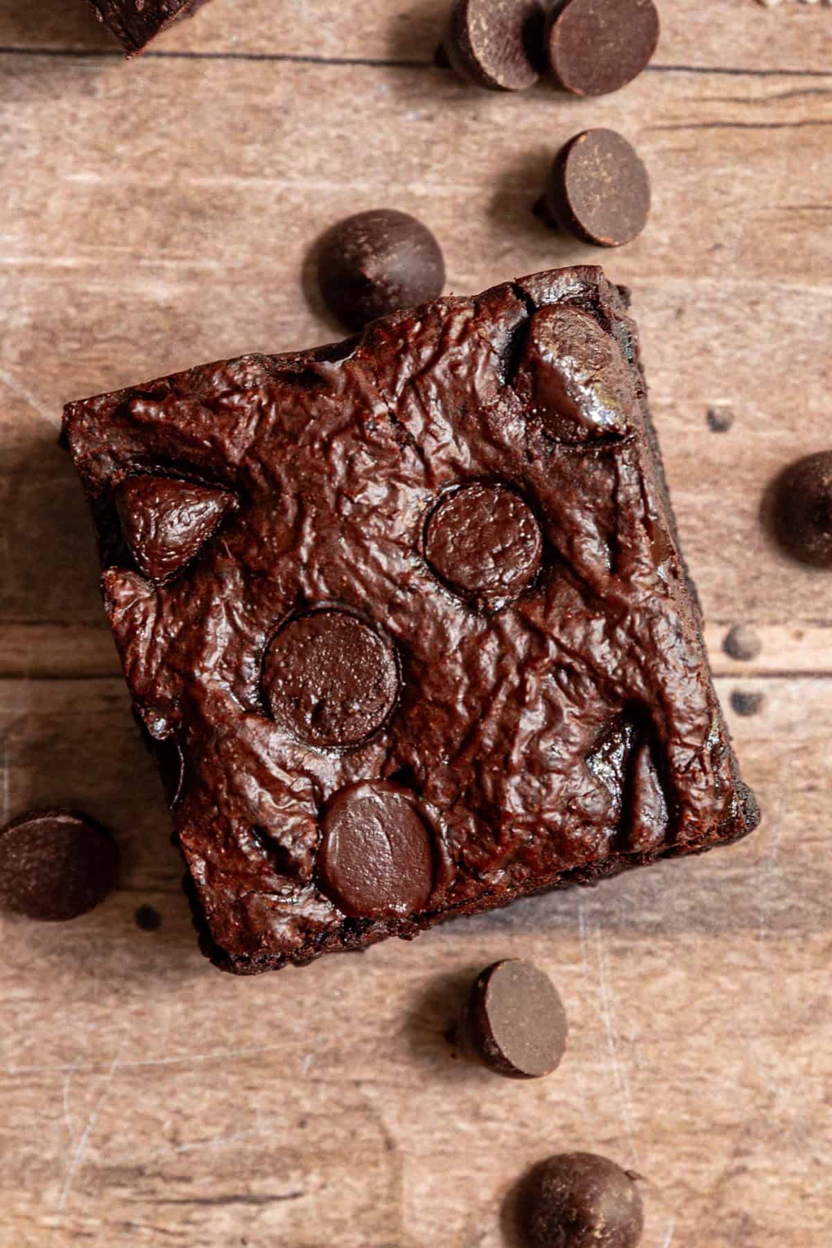 A wfpb brownie on a wooden table, with chocolate chips.