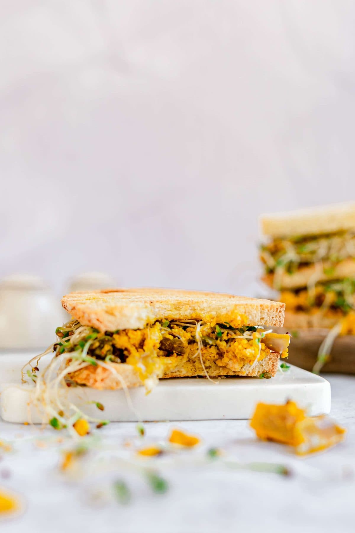 A tofu scramble sandwich with a bite taken.