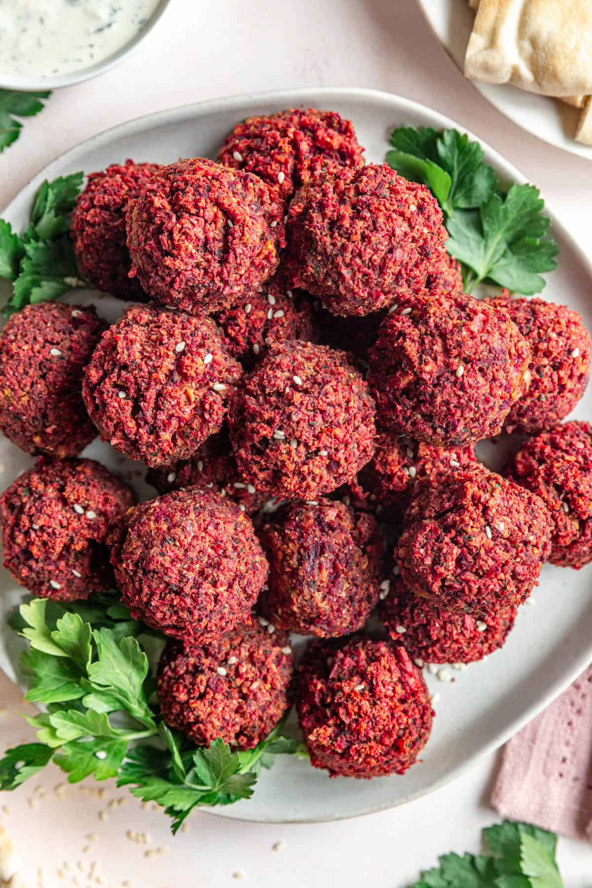 Baked Beetroot Falafel served with pita, tzatziki, parsley, and sesame seeds.