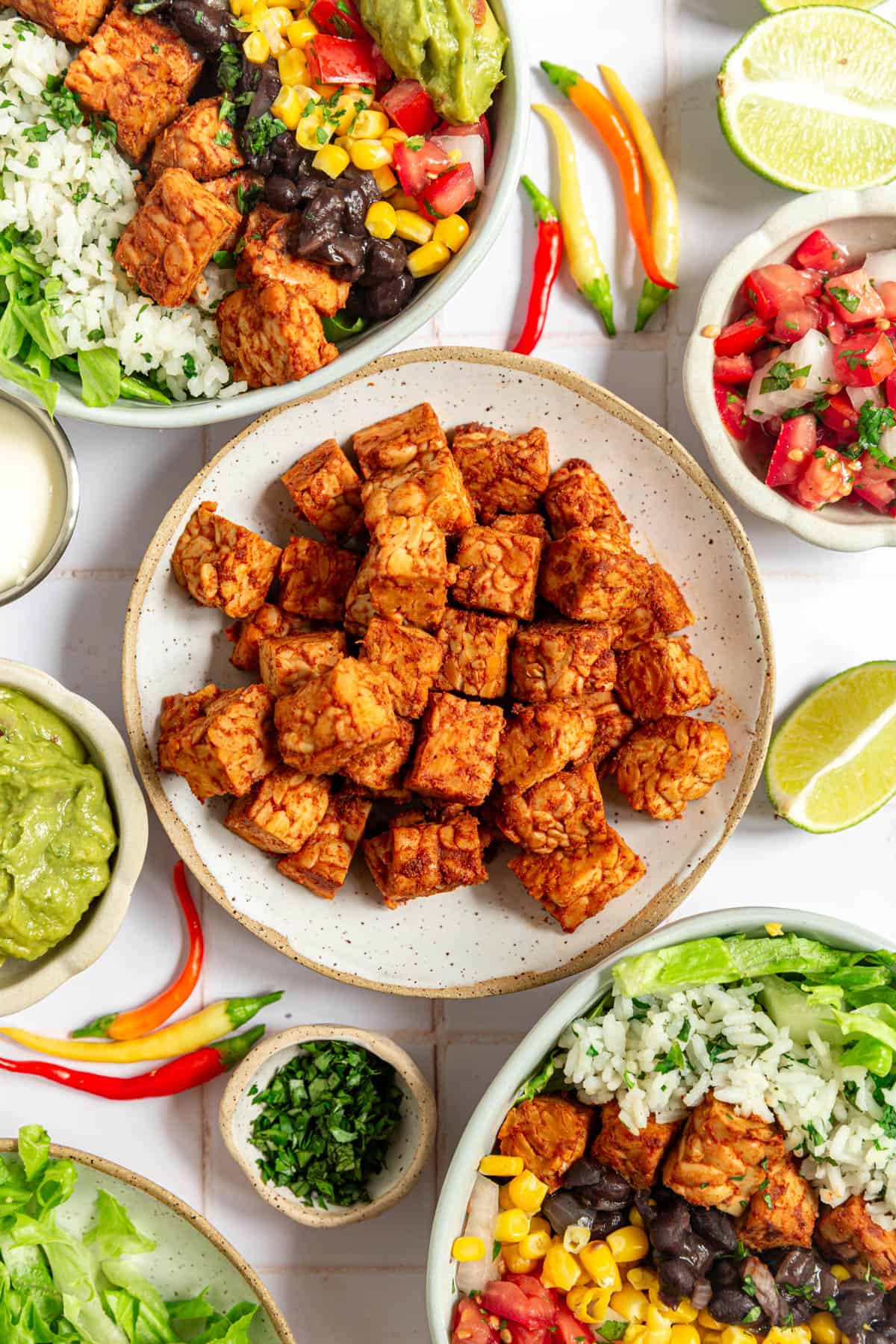 A bowl of cooked tempeh, with two tempeh burrito bowls.