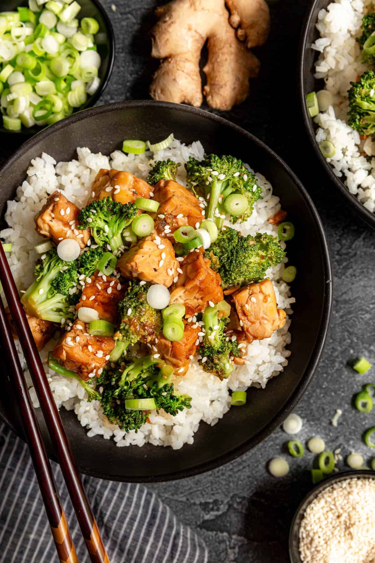 A bowl of teriyaki tempeh served on top of rice, with chopsticks.