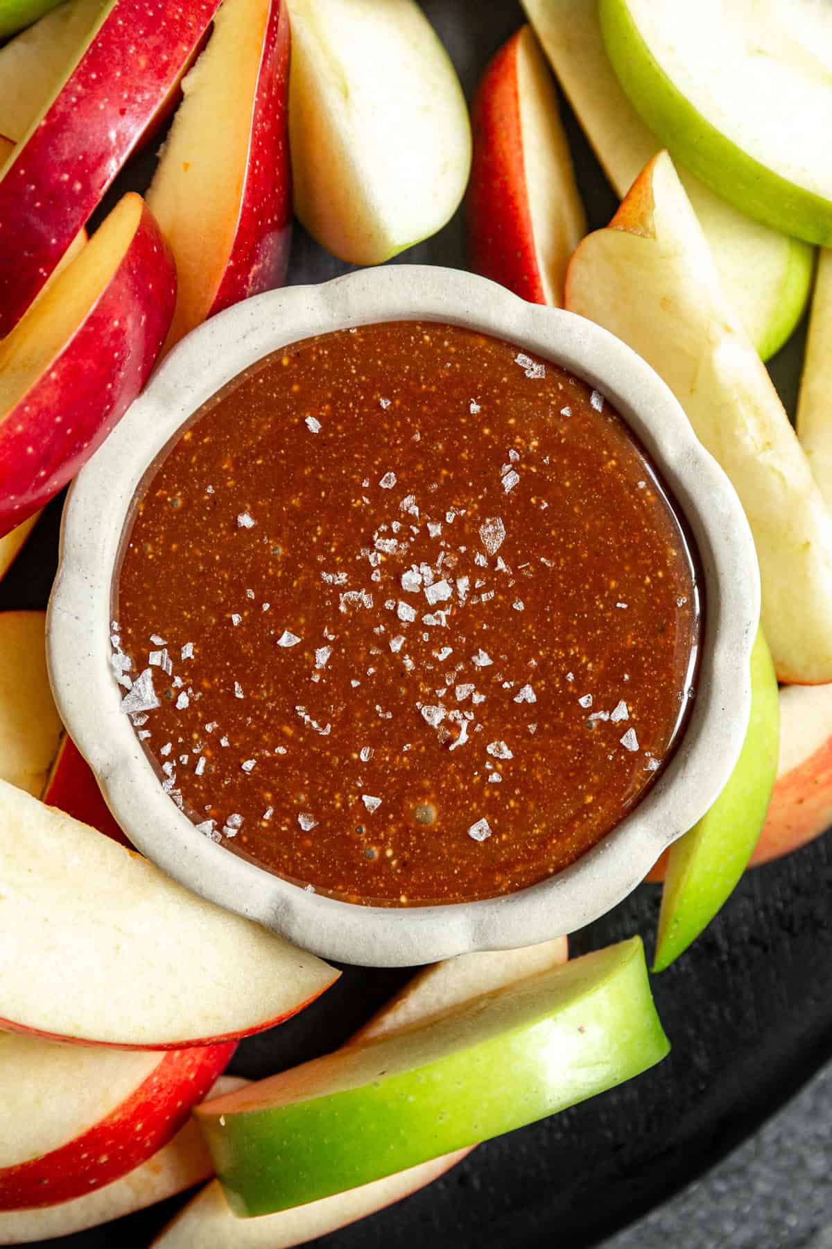 A bowl of vegan caramel served with apple slices.