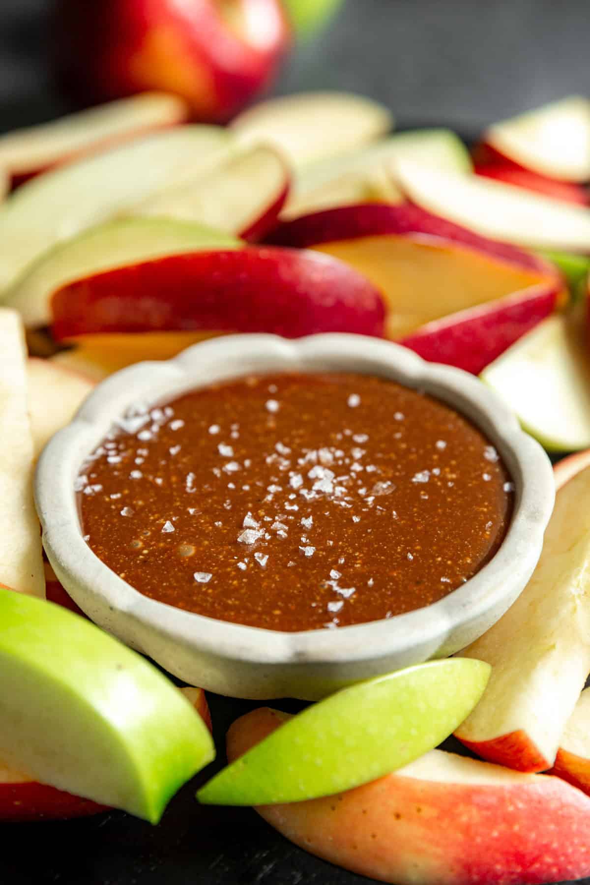 A bowl of vegan caramel served with apple slices.