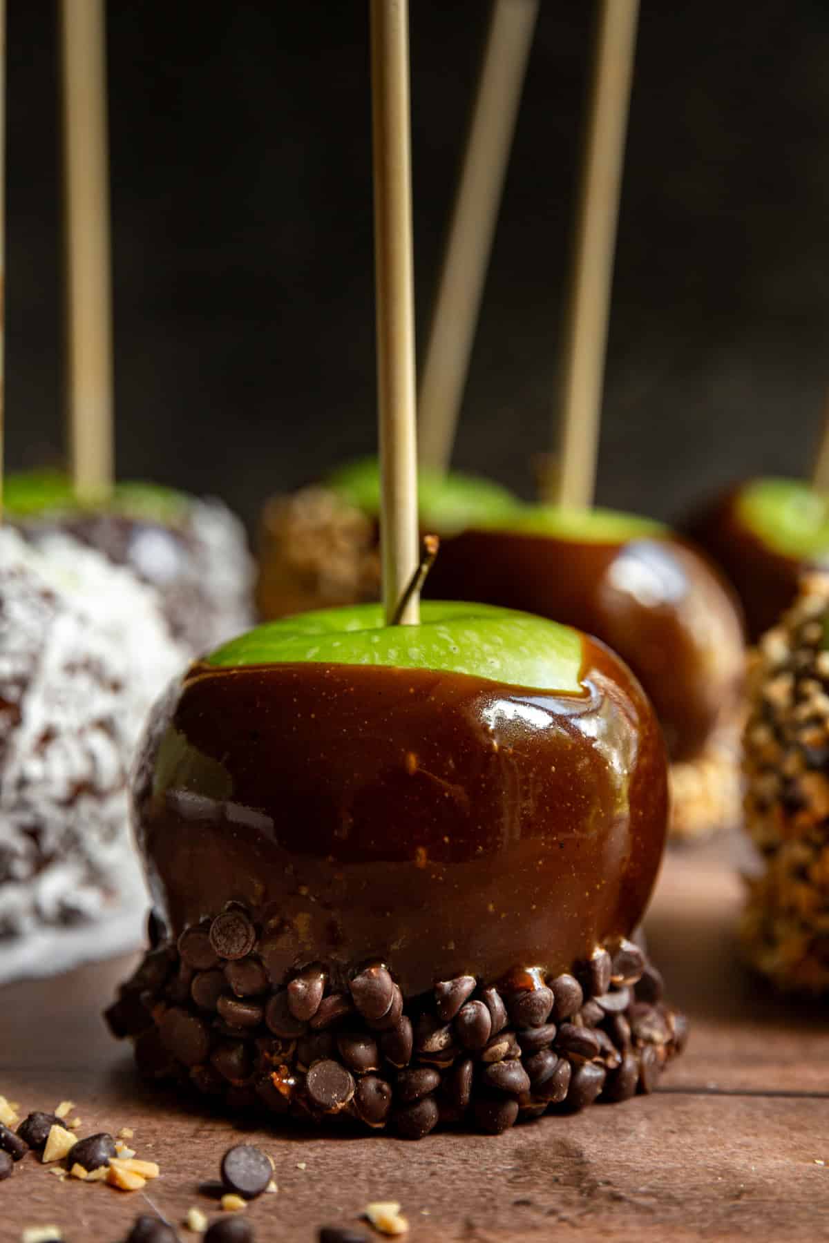 A vegan caramel apple covered partially in chocolate chips.