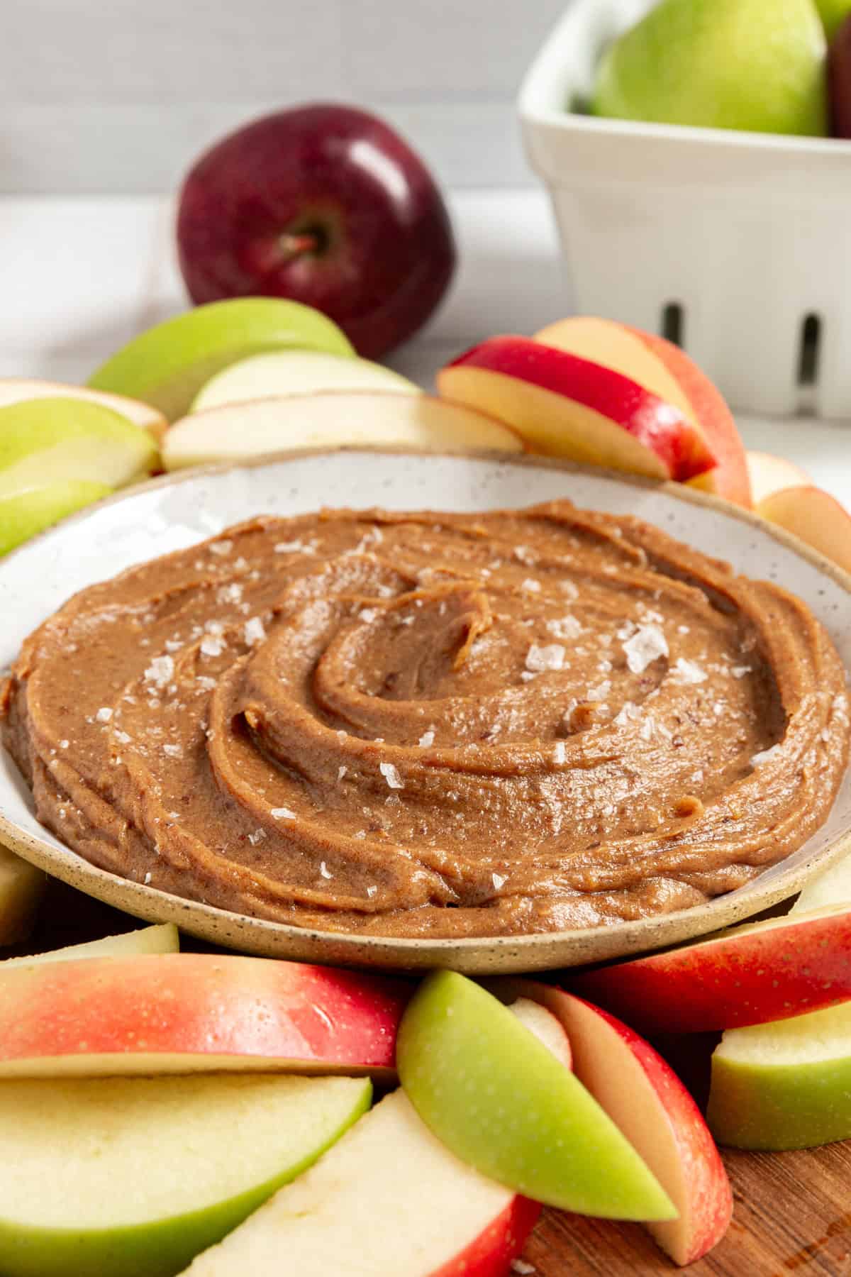 A tray of apples and a bowl of Vegan Date Caramel Sauce.