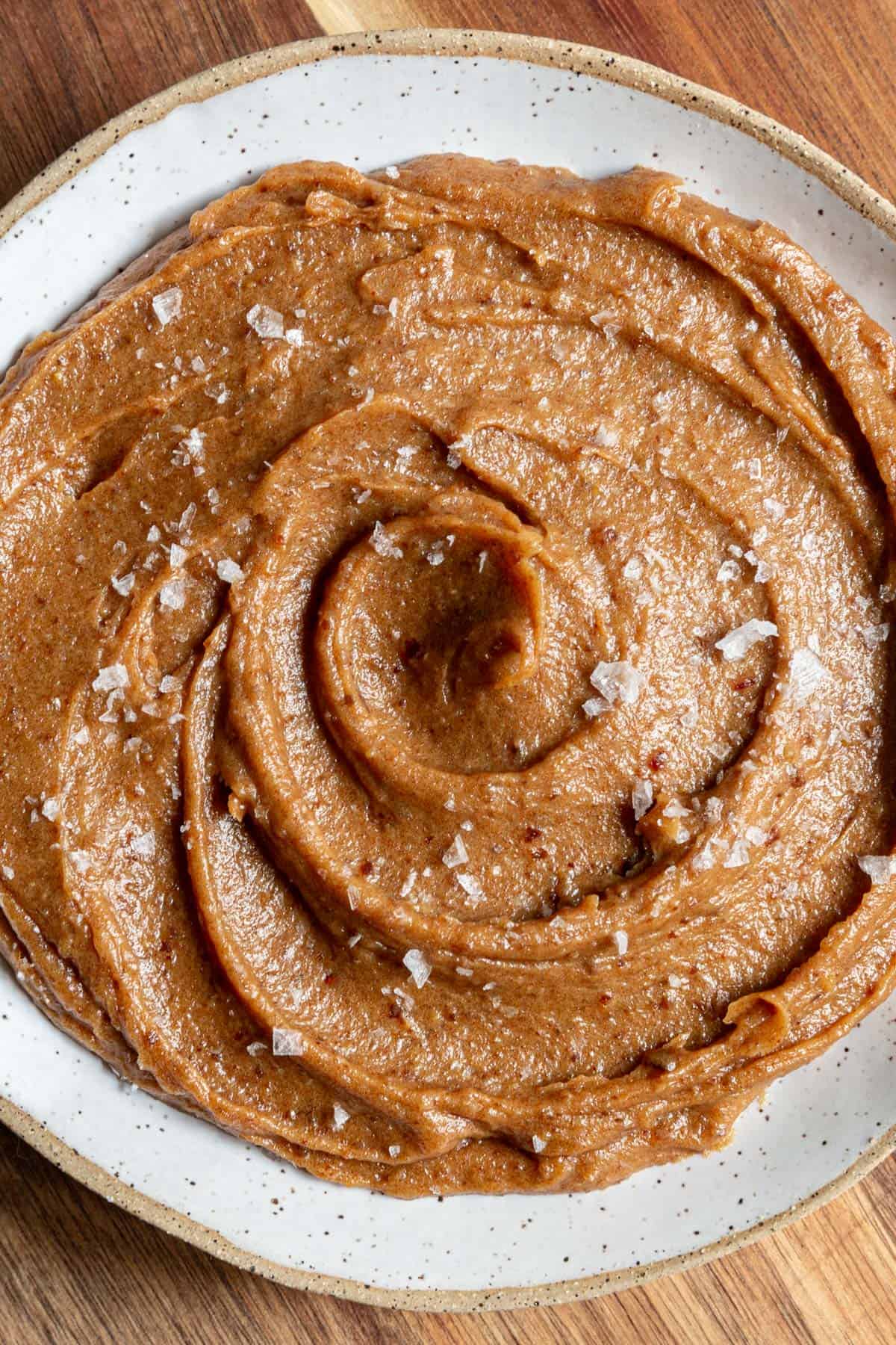 A bowl of vegan date caramel sauce, topped with sea salt.