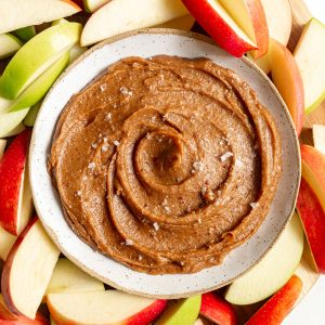 A tray of apples and a bowl of Vegan Date Caramel Sauce.