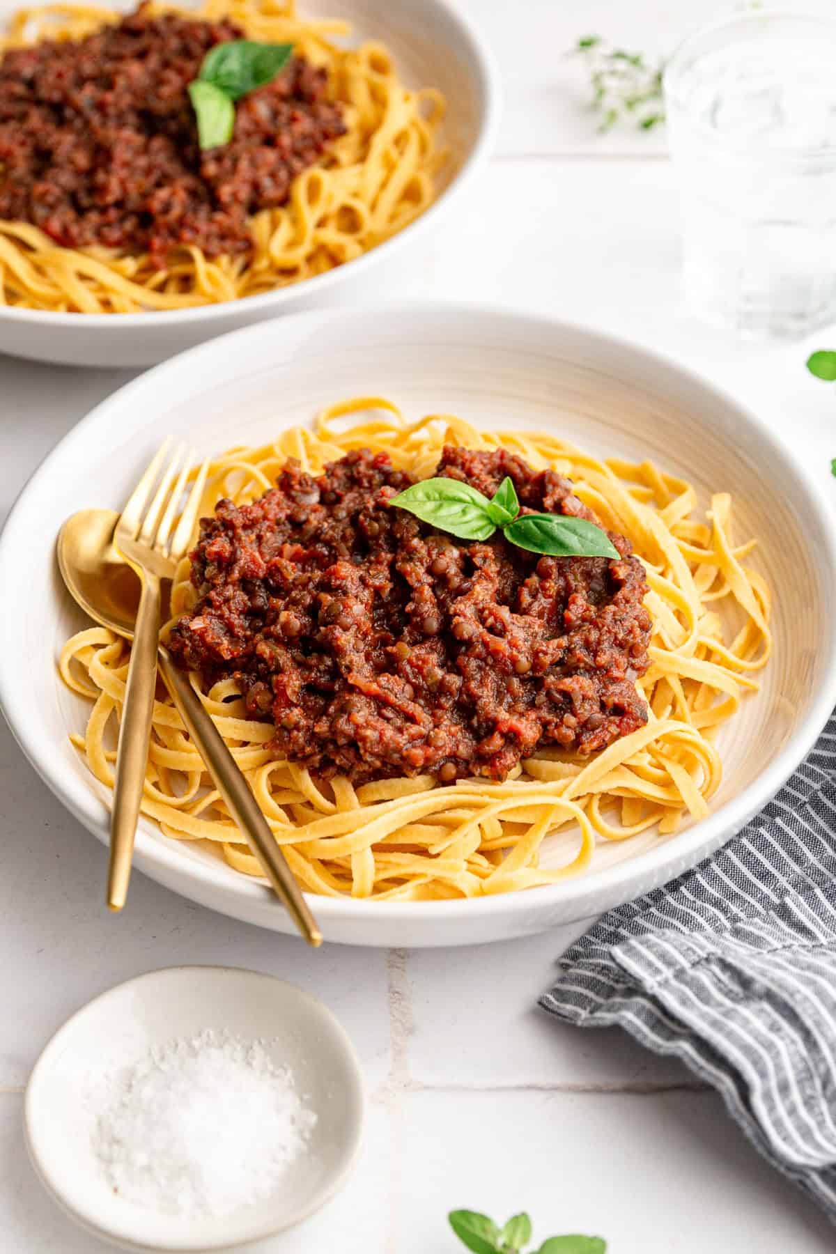 Two bowls of vegan black beluga lentil bolognese, ready to serve.