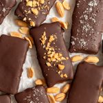 Several vegan butterfingers on a sheet of parchment paper, with peanuts.